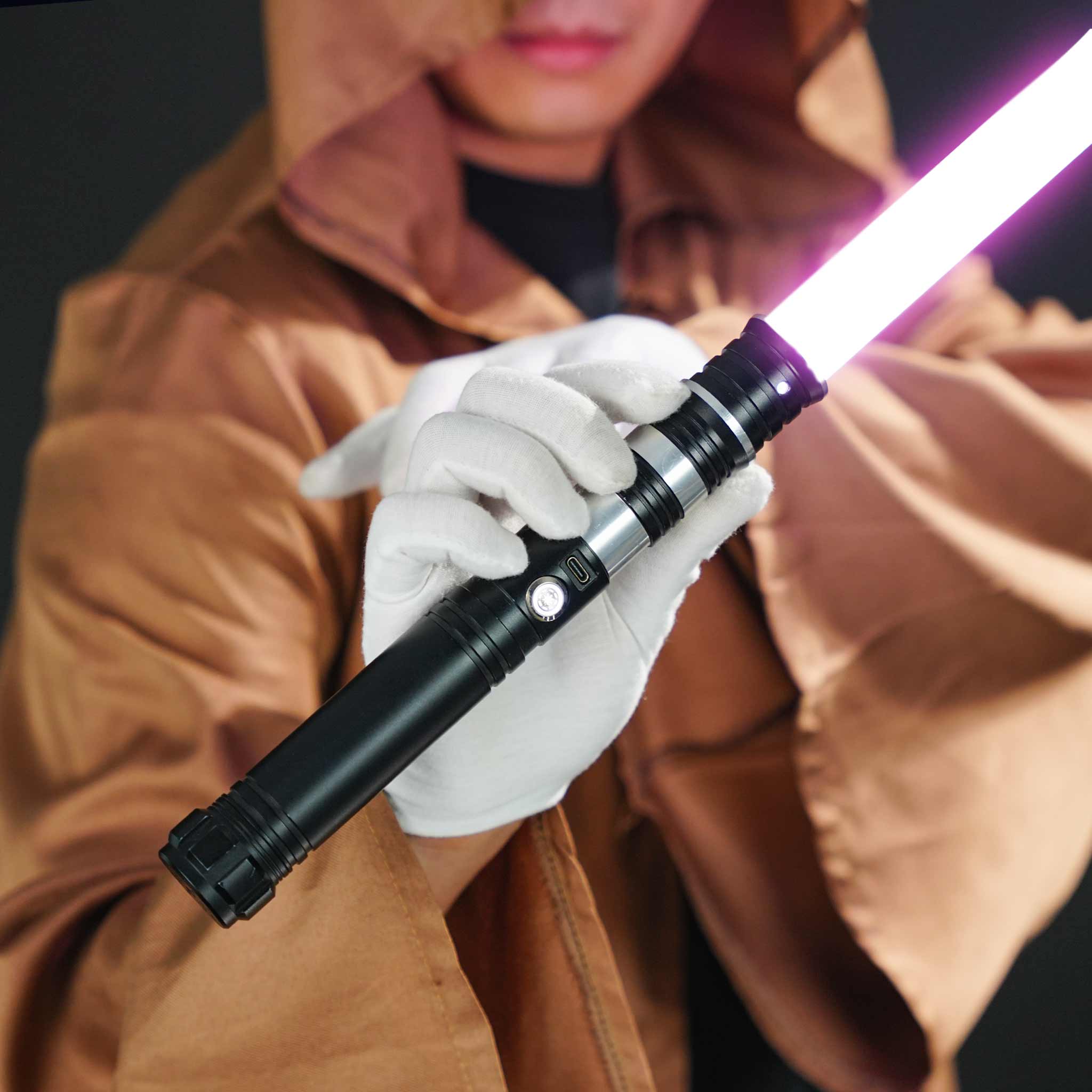 Cosplayer wearing a brown robe and white gloves holding the RGB Pixel dueling light saber with metal hilt