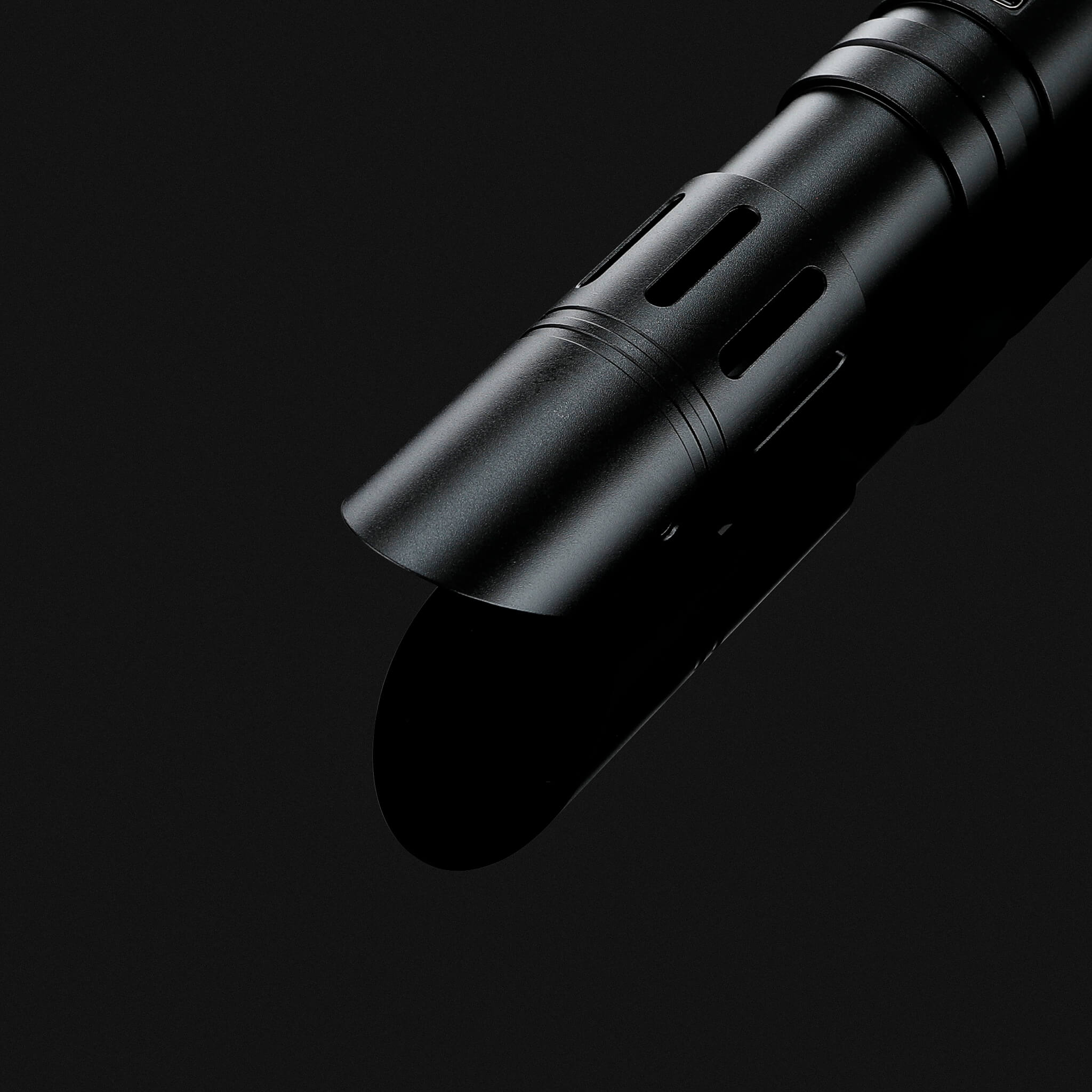 Detailed view of the aerodynamic slanted emitter crown on a black combat saber hilt
