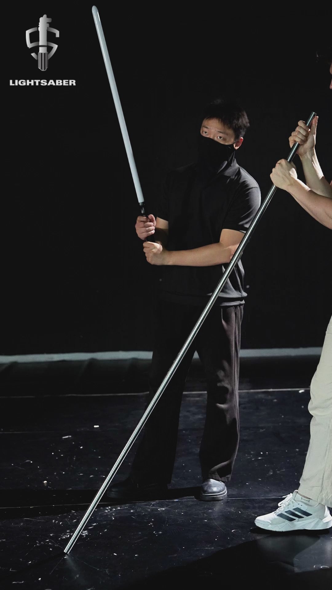 A dynamic product video showcasing the LIGHTSABER® Professional Heavy Dueling Combat Saber. A combatant performs full-contact spinning and realistic dueling maneuvers, showing off the bright infinite color-changing blade, the metallic silver aluminum hilt, and responsive smooth-swing motion effects.