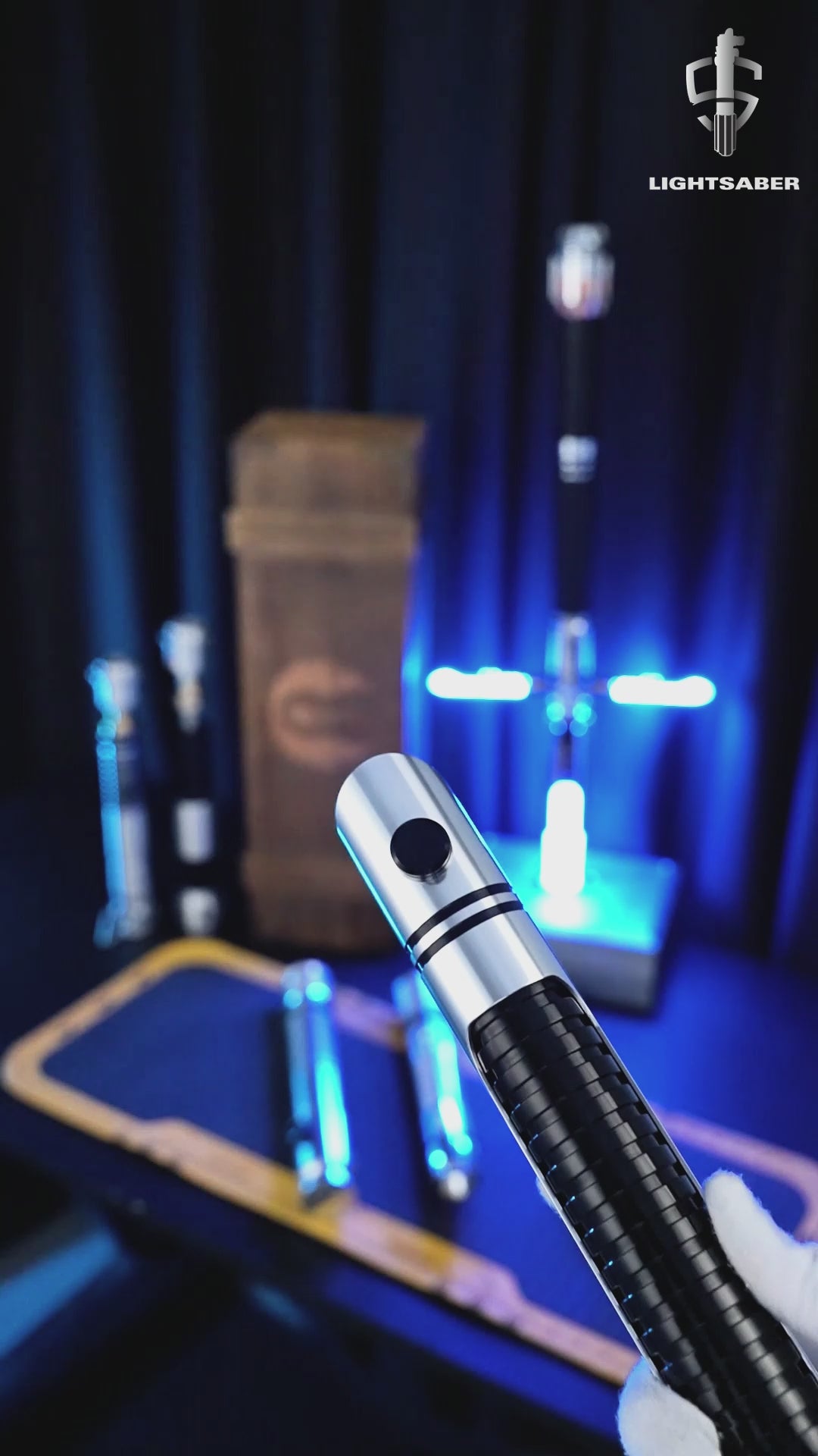 A detailed close-up of the Imperial Knight Saber prop showing its metallic silver and black hilt with a glowing illuminated blade